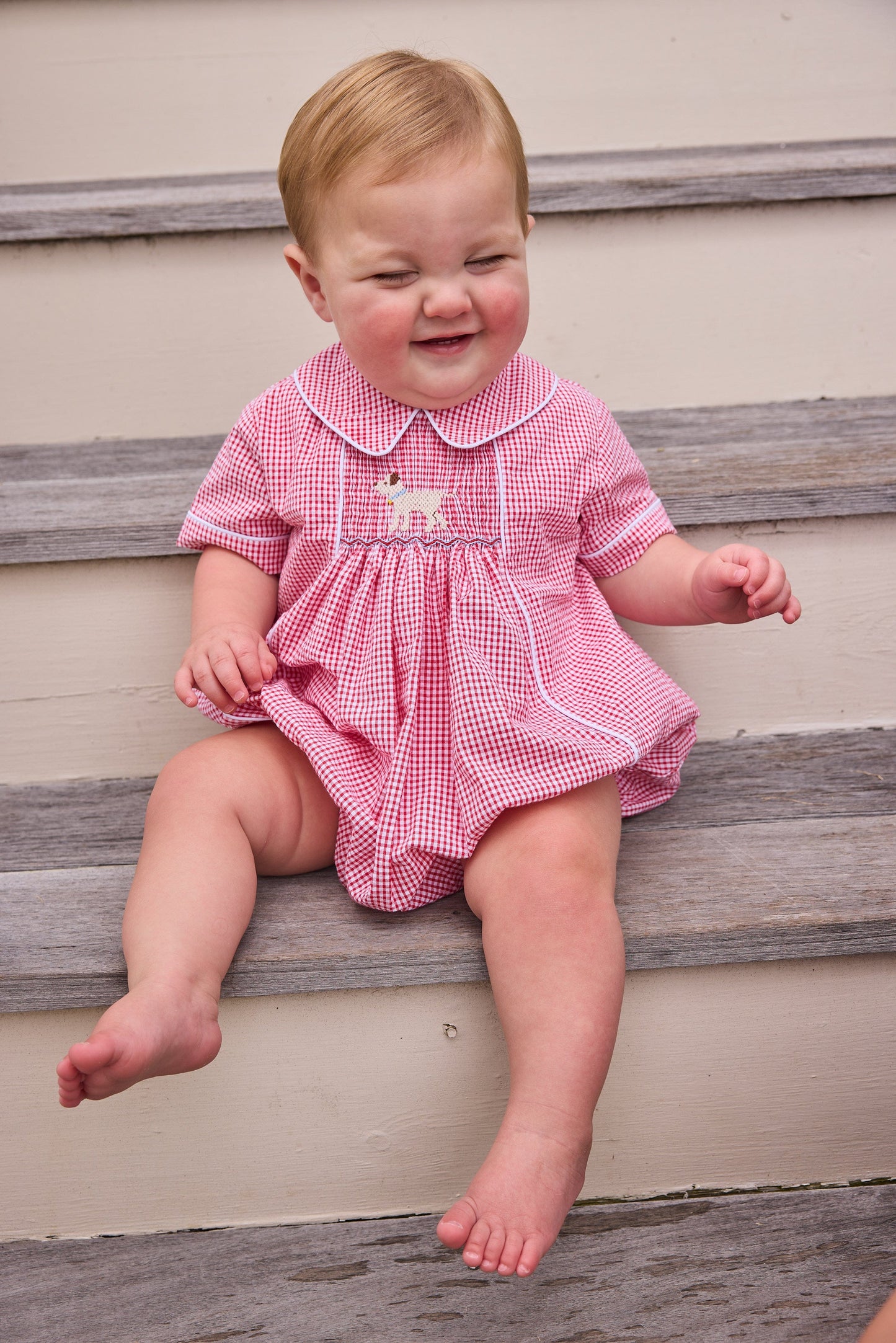 Little English traditional children's clothing. Classic peter pan bubble for baby boys in red seersucker gingham fabric and lab smocking at the chest