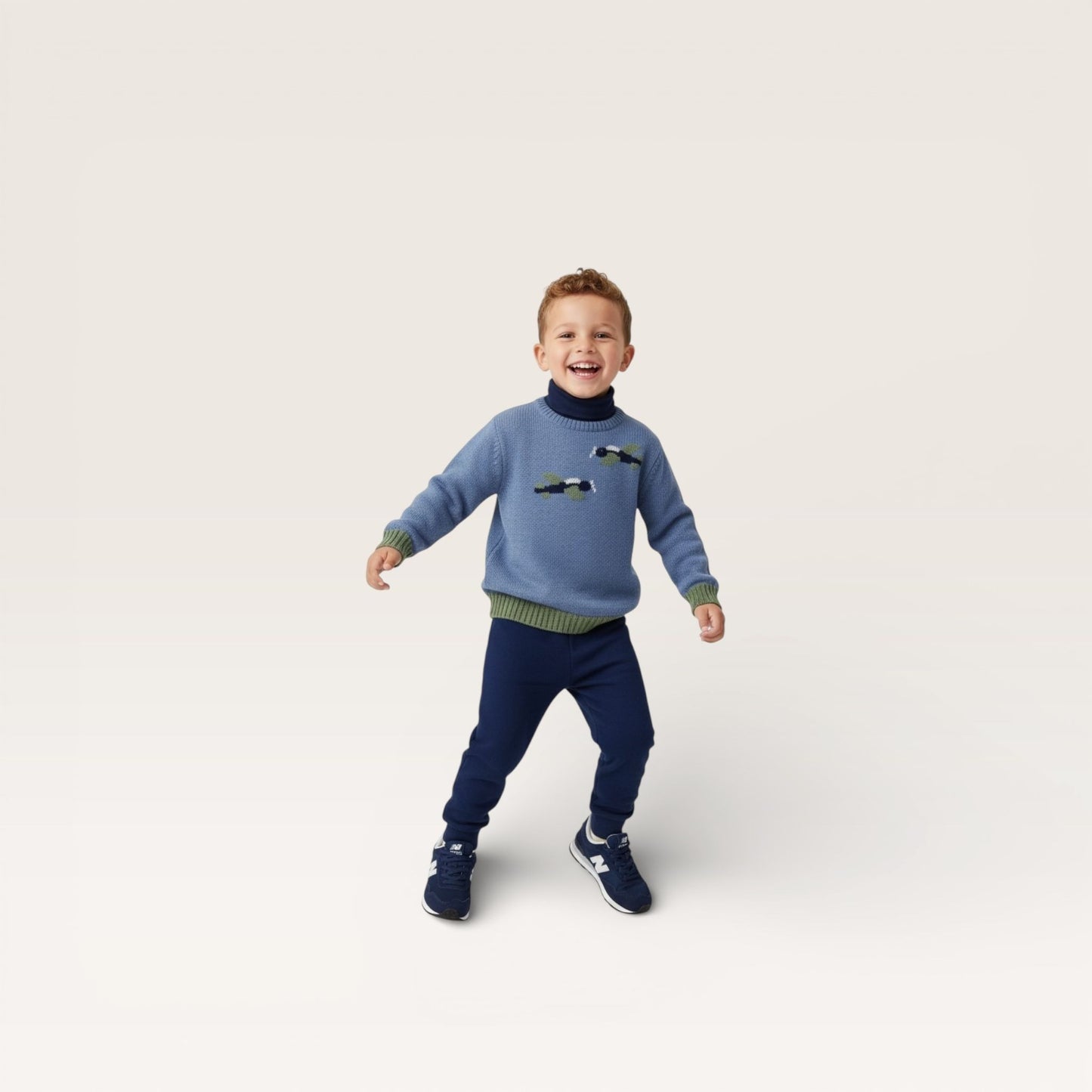 Child wearing a blue sweater with car designs and navy pants on a light gray background