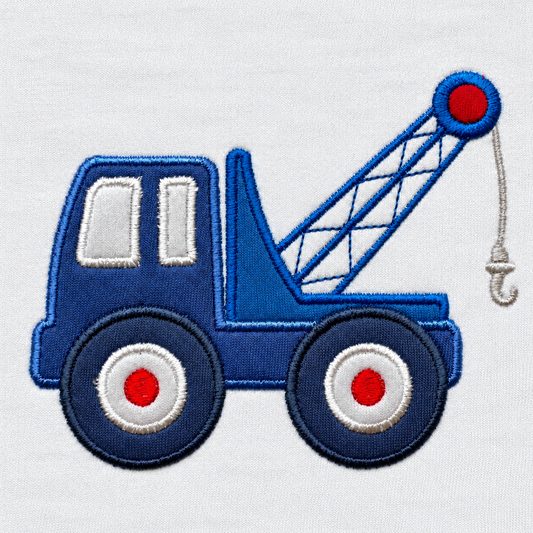 Close-up of the stitched blue tow truck appliqué with crane arm, hook and red wheel hubs