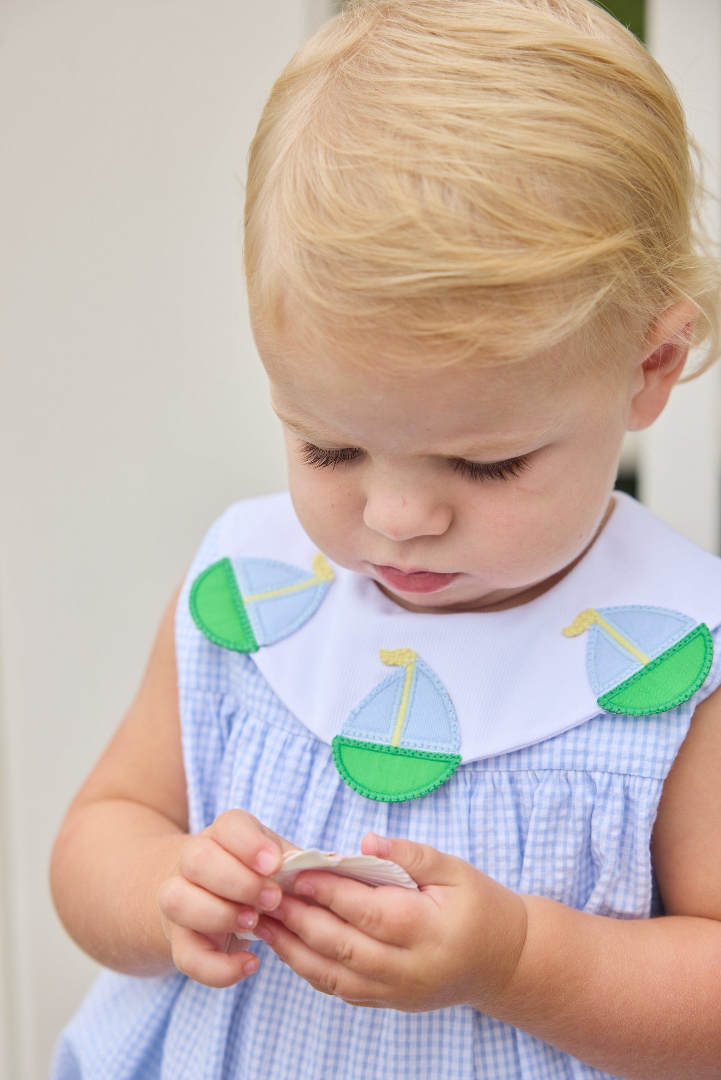 Little English traditional children's clothing.  Light blue seersucker gingham bubble with white bib collar and applique sailboats for baby girls.