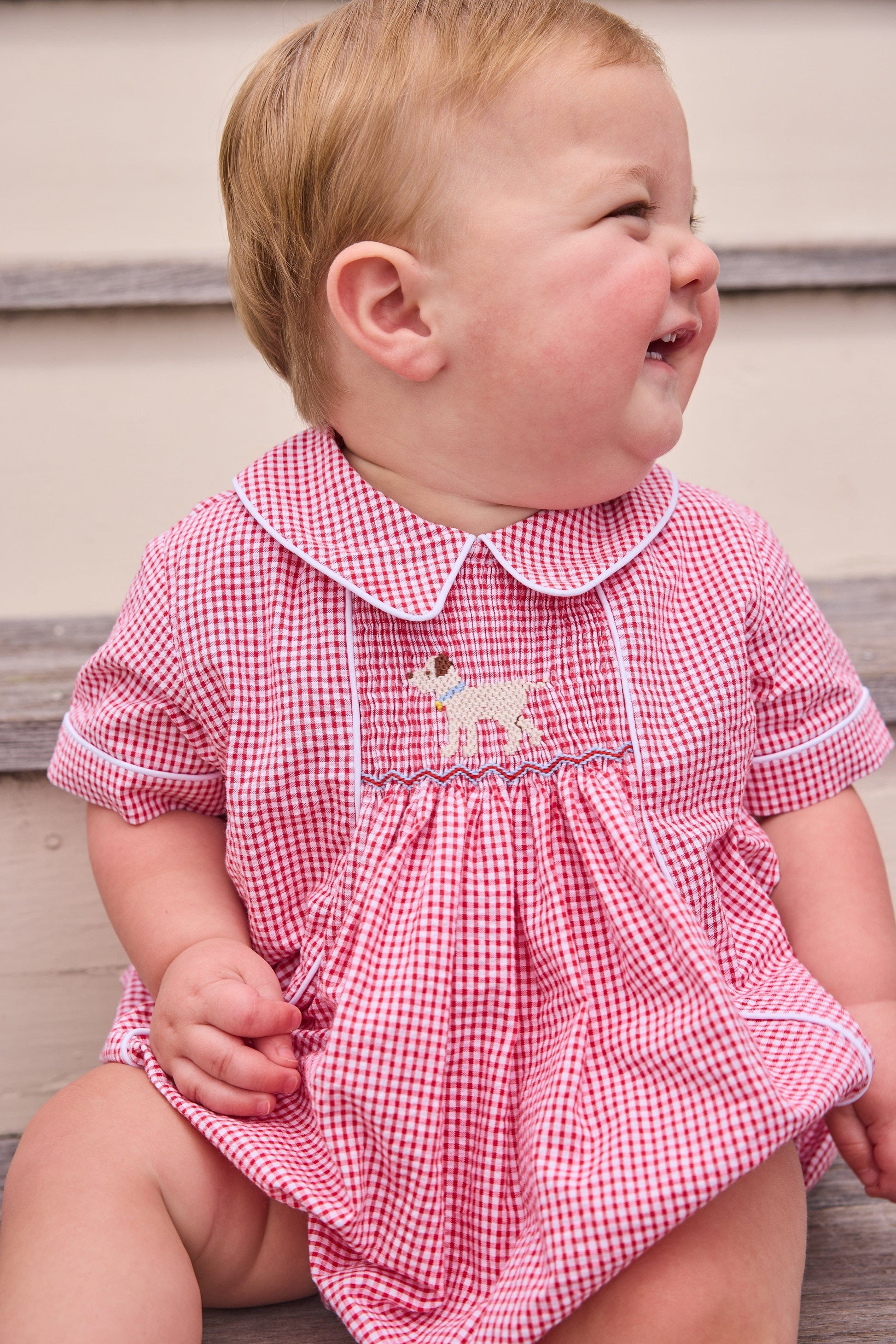 Little English traditional children's clothing.  Classic peter pan bubble for baby boys in red seersucker gingham fabric and lab smocking at the chest