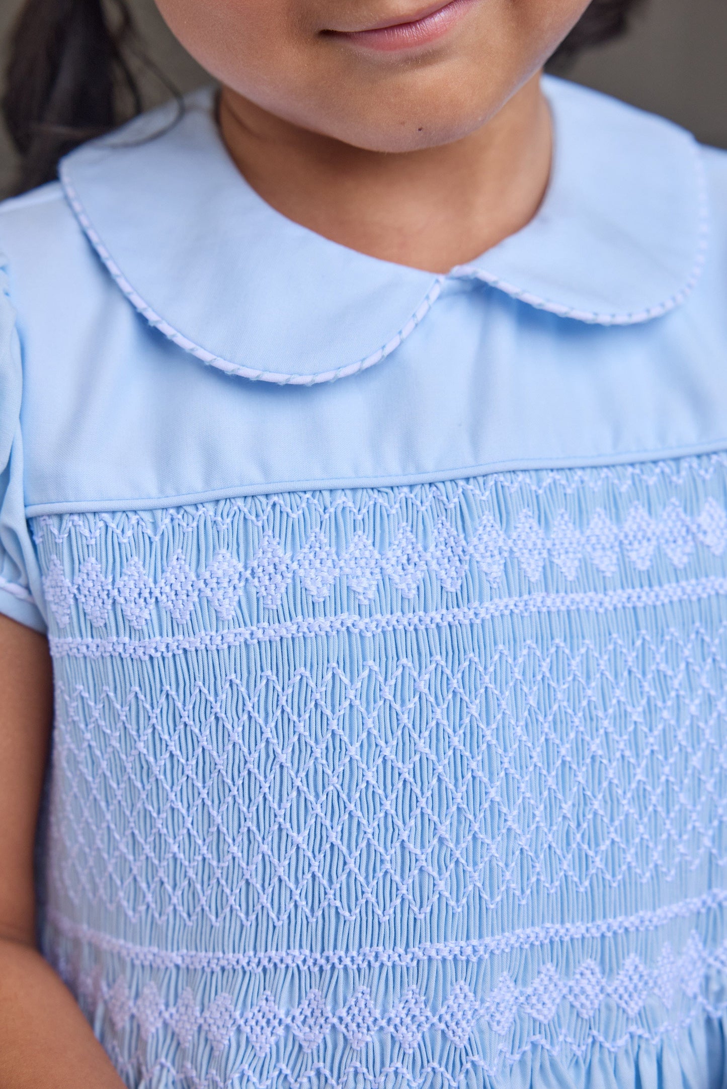 Little English classic smocked emery dress in light blue with white detailing, smocking around chest, tieable in back, for little girl 