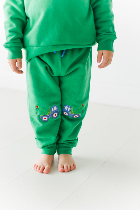 Toddler standing in the green Tow Truck Adventure Joggers, showing the tow truck appliqués on both knees
