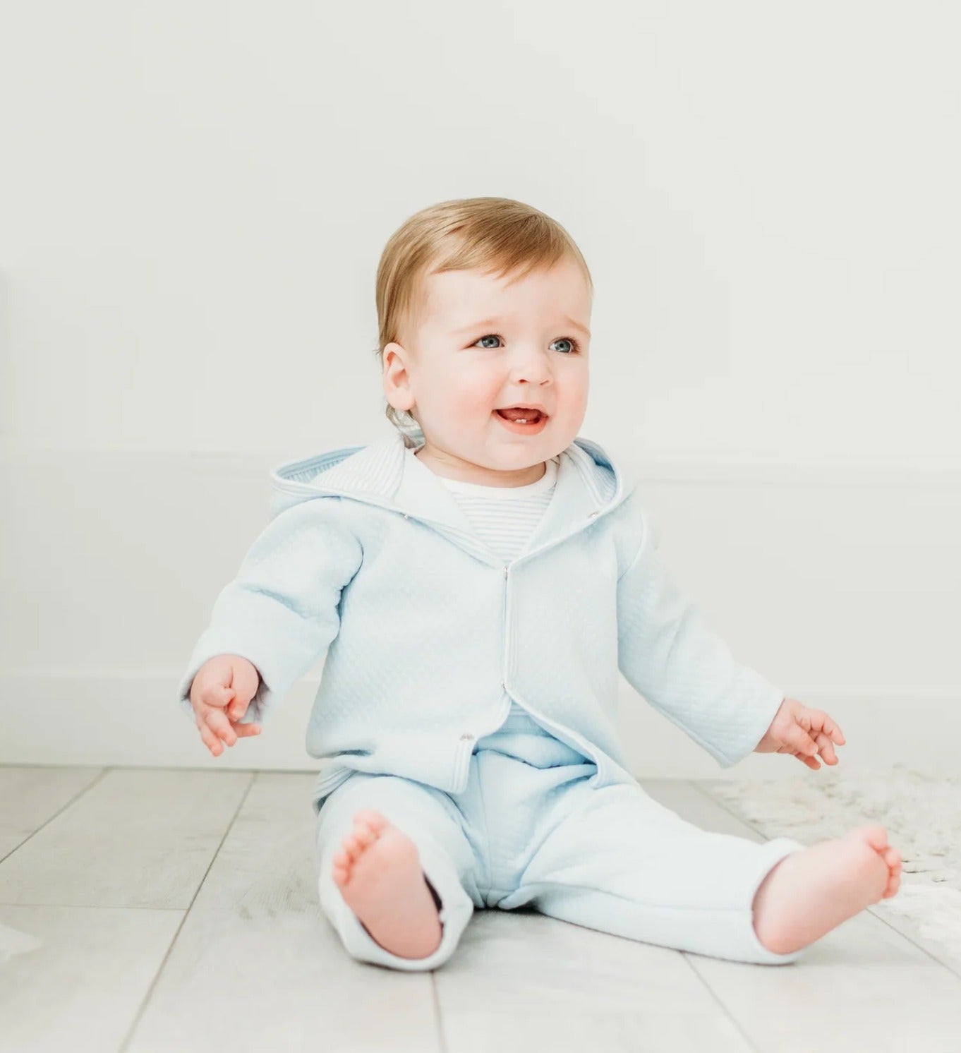 Baby Blue quilted button front hoodie and matching pants.  Worn by a baby boy sitting happily on a wooden floor. 