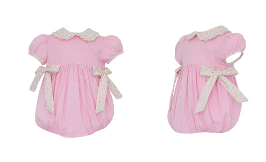 Two pink baby rompers with lace details on a white background