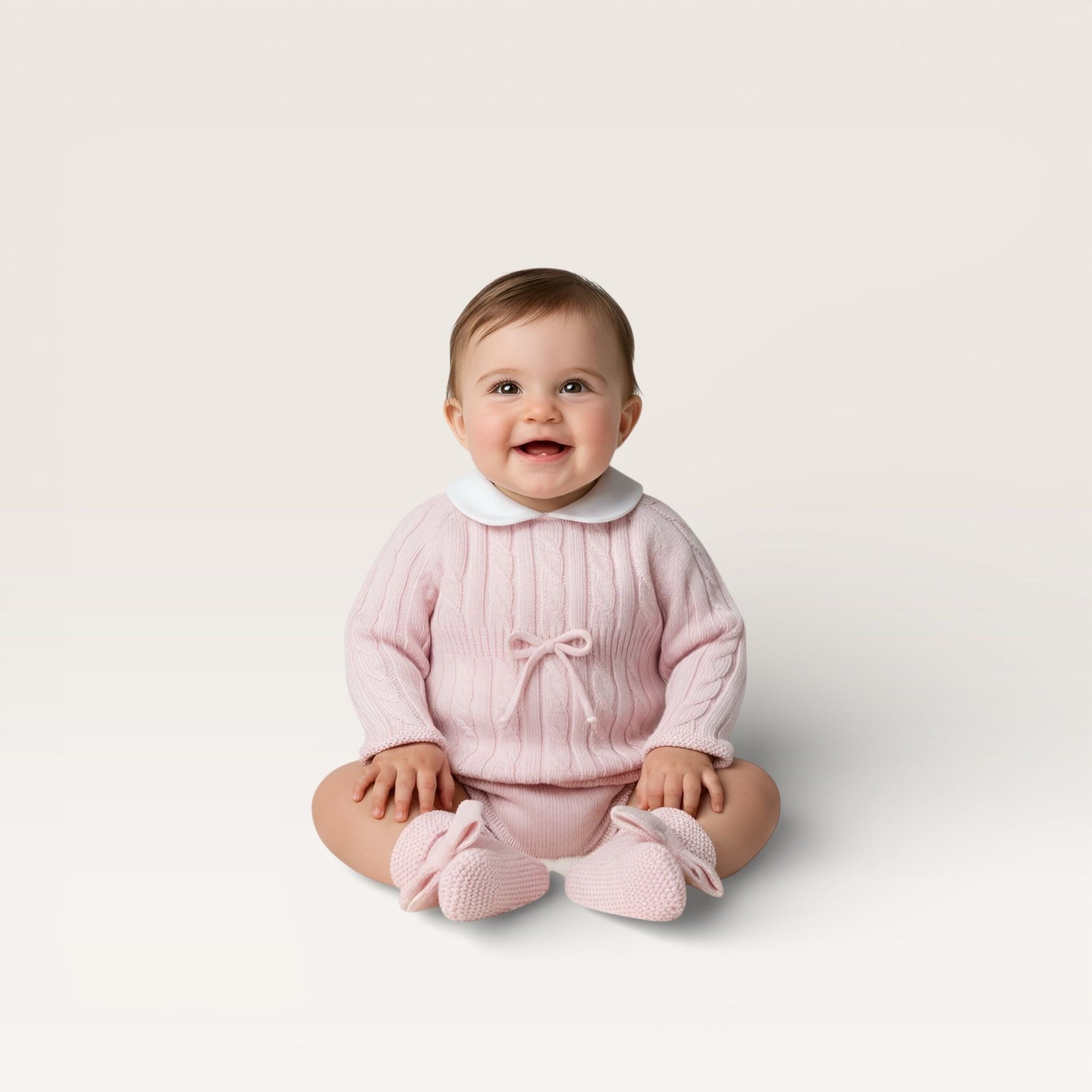 Baby wearing a pink outfit with a white collar on a light background
