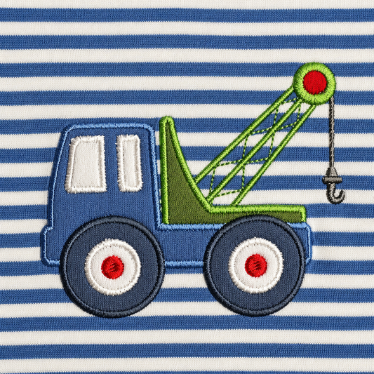 Close-up of the stitched tow truck appliqué with green crane arm, hook and red wheel hubs on blue and white stripes
