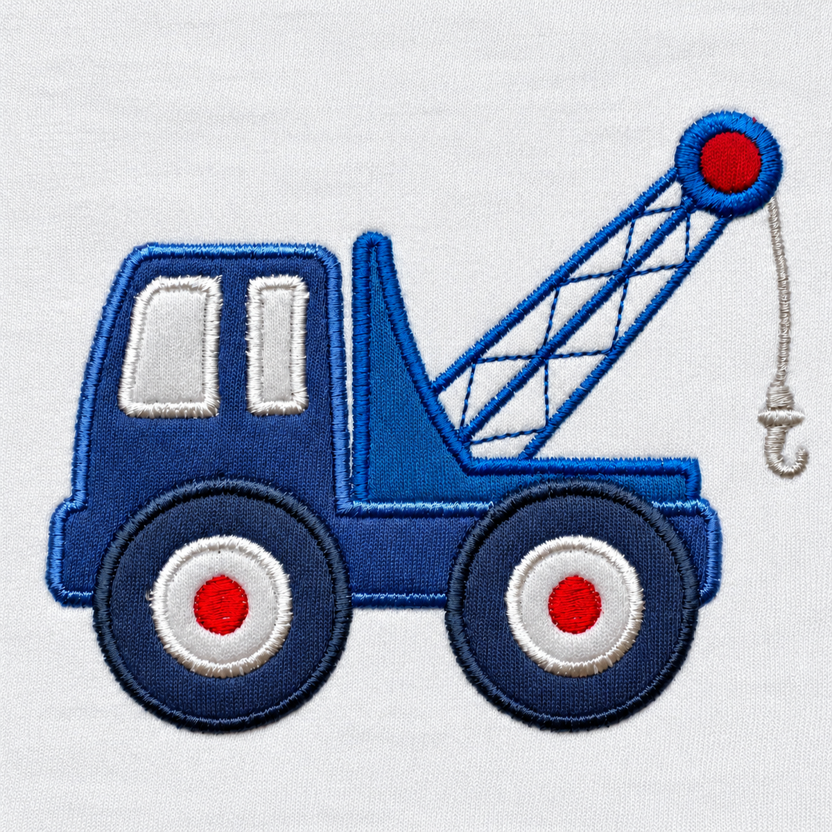 Close-up of the stitched blue tow truck appliqué with crane arm, hook and red wheel hubs